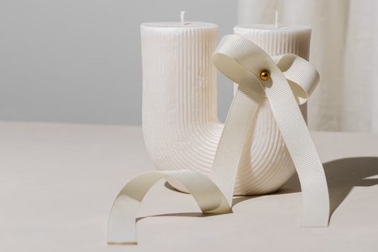 U-shaped candle with white flowing ribbon tied meticulously and elegantly around it.