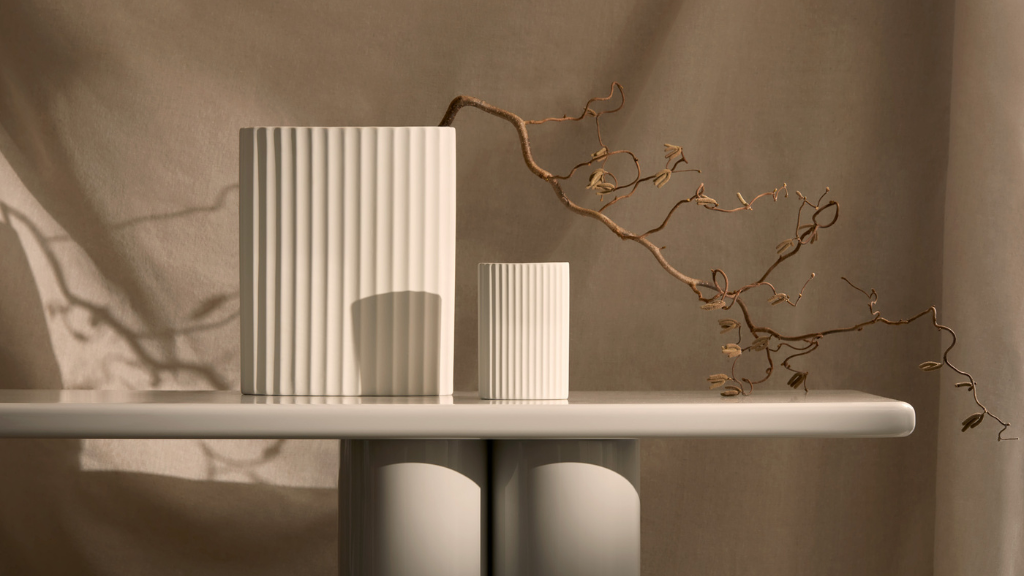 Ivory white ceramic textured vases in two sizes showcased on a marble table with a floral branch placed in the largest vase.