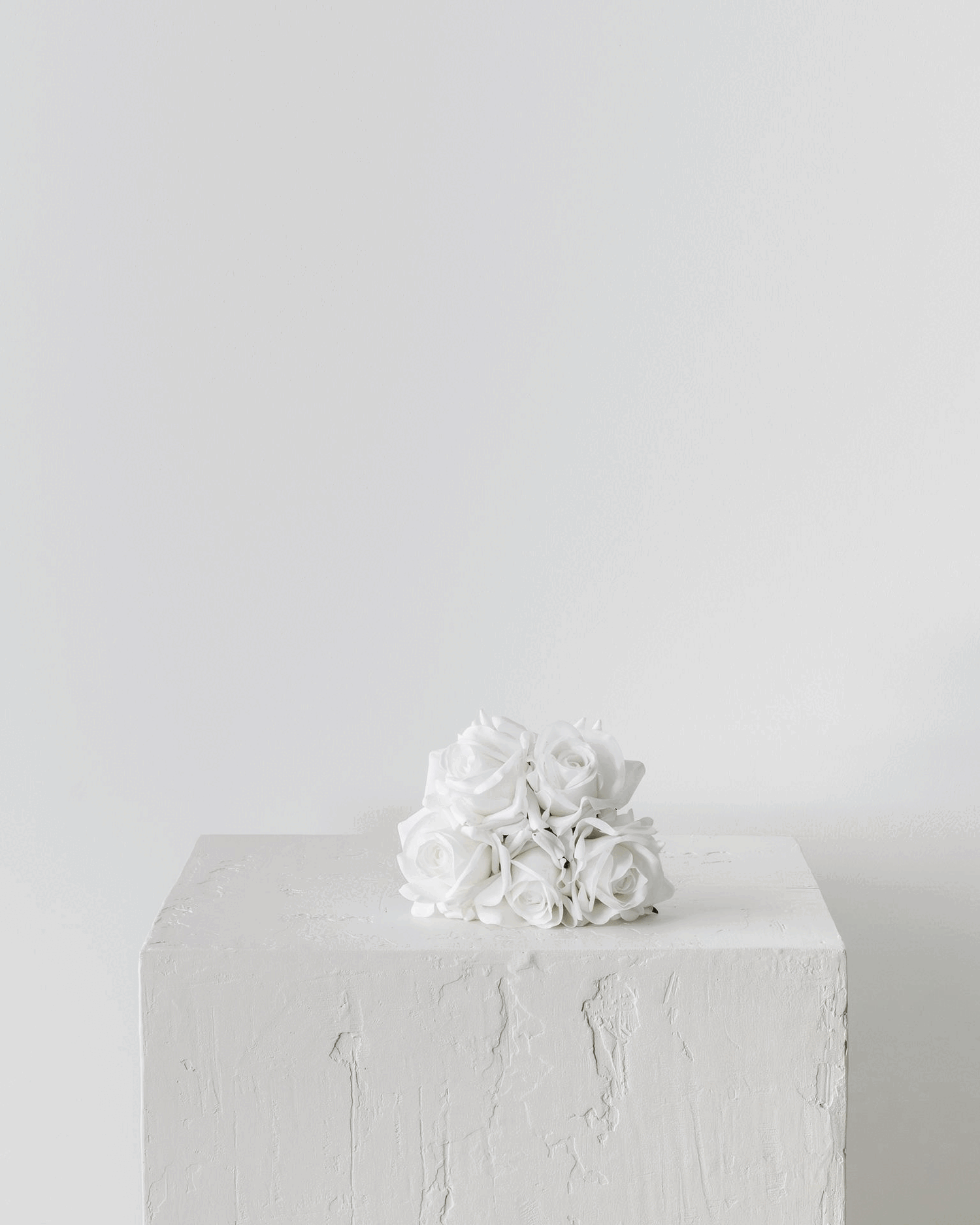 A GIF showcasing three sizes of white rose real-touch bridal bouquets elegantly displayed on a plinth